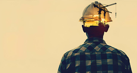 an graphic of a person wearing a hardhat with cranes and a sunset within the hardhat