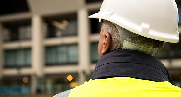 a man wearing a white helmet looking at a building site